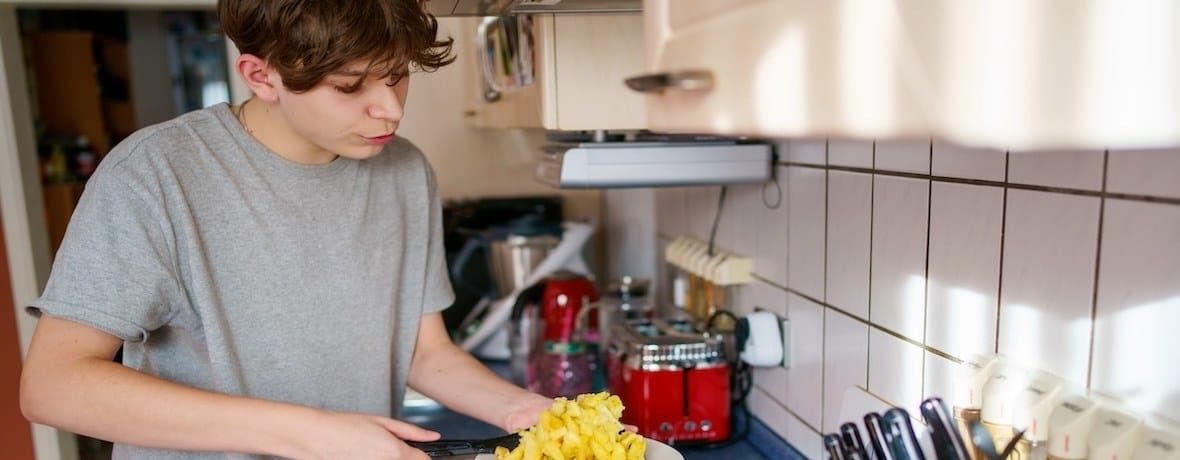 Teenager cooking a meal independently in the home kitchen